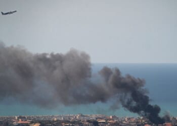 A MEA commercial airplane is flying above the smoke after an IDF airstrike on March 17, 2026, in Beirut, Lebanon.
