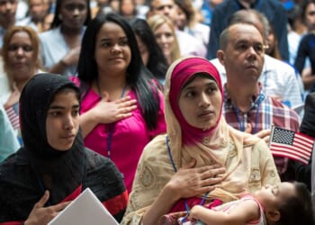 Mosammat Rasheda Akter, originally from Bangladesh, holds her 7-month-old daughter Fahmida as she recites the Pledge of Allegiance after officially becoming a U.S. citizen during a naturalization ceremony at the New York Public Library on July 3, 2018, in New York City.