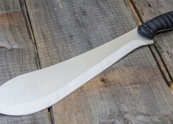 A machete is pictured on a wooden table.