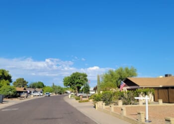 A residential street in Phoenix, Arizona, showcases single-story ranch homes and classic southwestern desert xeriscape landscaping.