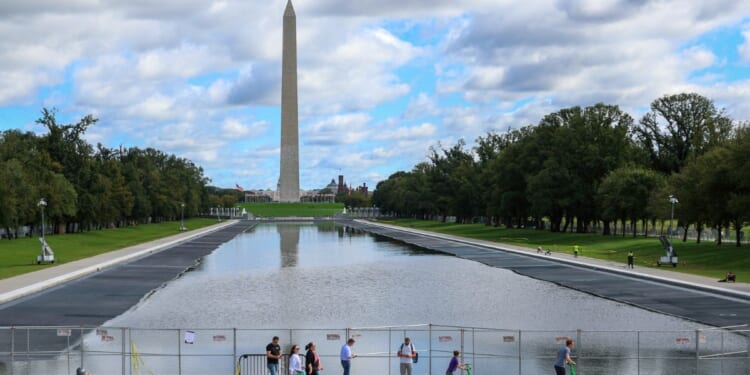 Visitors walk past the reflecting pool as it is refilled on Monday, Oct. 12, 2026.