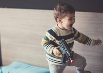 A kid plays with a BB gun.