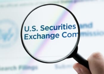 The Securities and Exchange Commission logo is viewed on a website through a magnifying glass.
