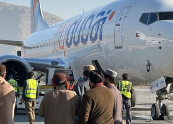 People stand on a tarmac next to a Flydubai airline after it landed in Kabul International Airport in Kabul on Nov. 15, 2023.