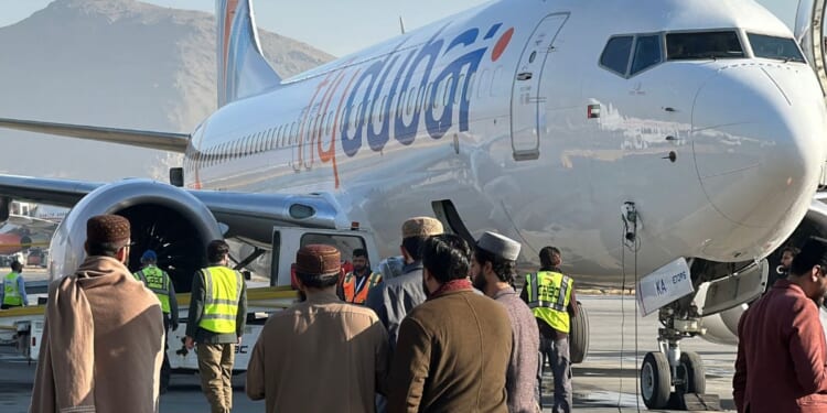 People stand on a tarmac next to a Flydubai airline after it landed in Kabul International Airport in Kabul on Nov. 15, 2023.