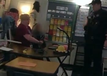 A police officer interviews a teacher holding a 6-year-old who just shot another teacher in Richneck, Virginia, in 2023.
