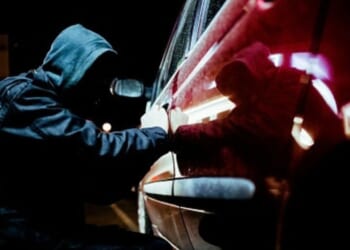 A thief tries to pry open a car door.
