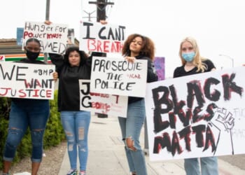 Young women wear protective masks and hold signs in support of Black Lives Matter on May 28, 2020, in Marina del Rey, California.