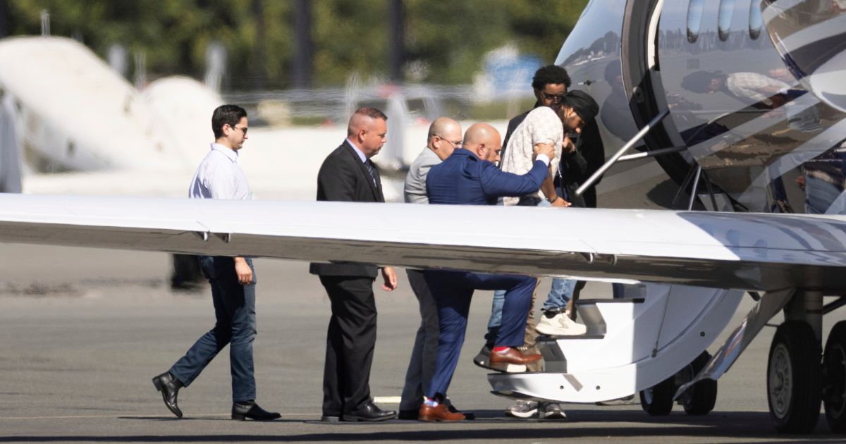 Harjinder Singh, right, is escorted onto an airplane by Florida Lt. Gov. Jay Collins and law enforcement in Stockton, California, on Thursday.