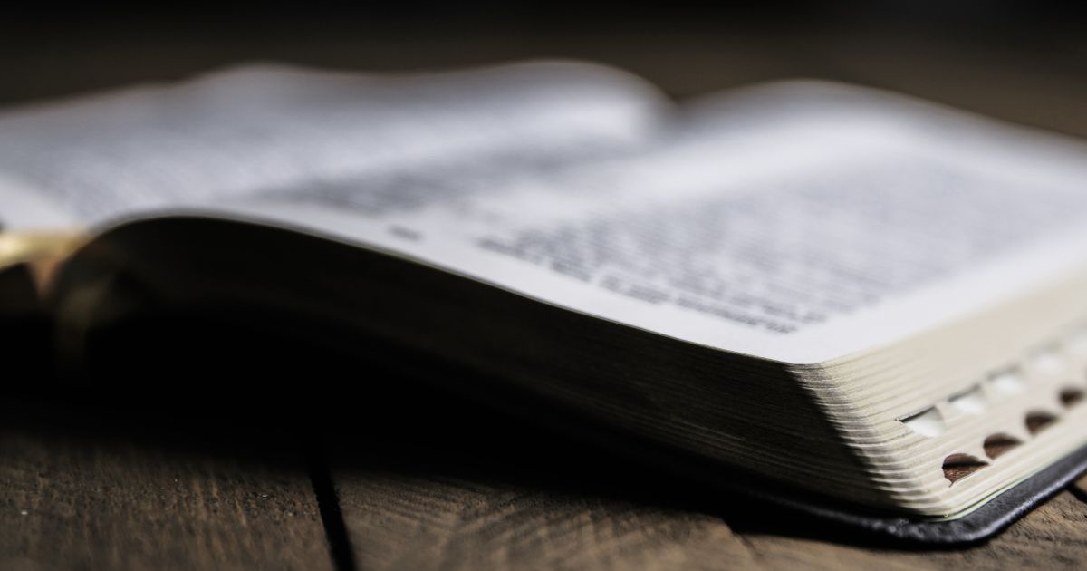 A Bible lays open on a wooden table.