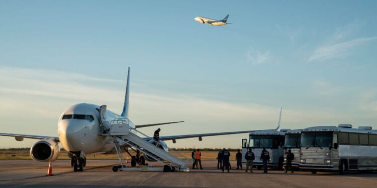 Buses transporting migrants to board the first deportation flight of illegal alien Venezuelans are seen as another deportation plane headed to Central America is seen flying above them in Harlingen, Texas, on Oct. 18, 2023.