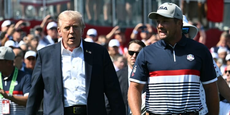 President Donald Trump walks with pro golfer Bryson DeChambeau as he attends the 2025 Ryder Cup at Black Course at Bethpage State Park Golf Course on Sept. 26, 2025, in Farmingdale, New York.