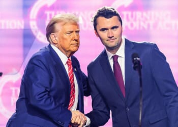 This photo taken on Dec. 22, 2024, shows conservative activist Charlie Kirk shaking hands with President Donald Trump as he speaks on stage at America Fest 2024 in Phoenix, Arizona.