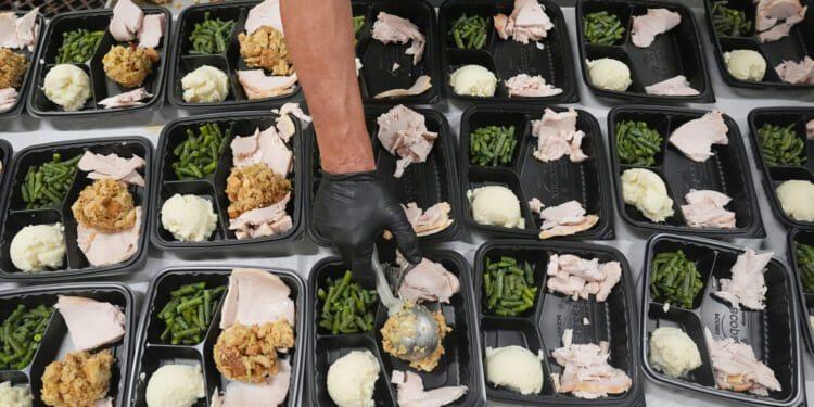 A volunteer prepares meals Thursday at the Philabundance Community Kitchen in Philadelphia.