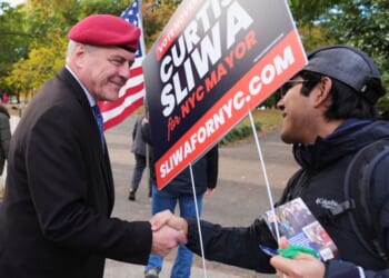 New York City mayoral candidate Curtis Sliwa, left, shakes hands with a volunteer Tuesday in the Queens borough of New York