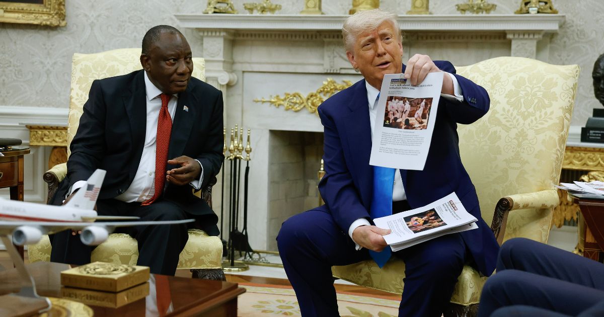 President Donald Trump holds up a printed article from "American Thinker" while accusing South Africa President Cyril Ramaphosa of state-sanctioned violence against white farmers in South Africa during a press availability in the Oval Office at the White House on May 21, 2025, in Washington, D.C.