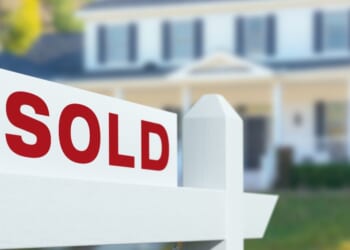 This stock image shows a home with a "Sold" sign in the front yard.