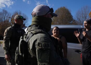 Department of Homeland Security Investigations officers question an individual after two people fled the scene while being stopped for selling flowers on the side of the road on Nov. 16, 2025, in Charlotte, North Carolina.