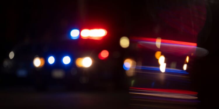 A blurred photograph of police lights flashing on a city street.