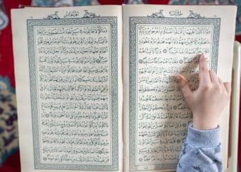 A close up of a boy reading the Quran.