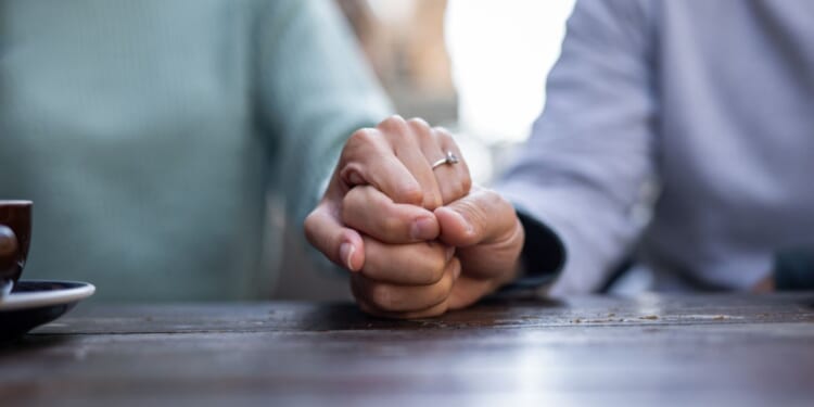 A couple holds hands at a cafe table.