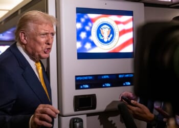 President Donald Trump speaks to reporters aboard Air Force One on Friday while in flight from Washington to West Palm Beach International Airport.