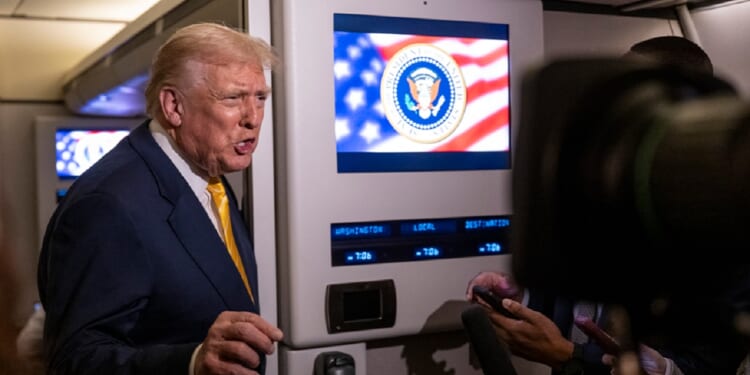 President Donald Trump speaks to reporters aboard Air Force One on Friday while in flight from Washington to West Palm Beach International Airport.