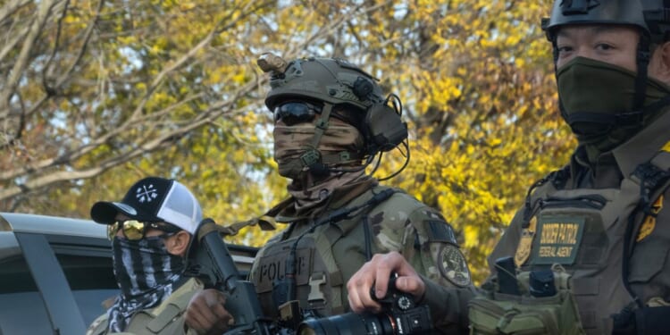 Federal agents searching for illegal aliens in Chicago, Illinois, as a part of Operation Midway Blitz pause to regroup in a park on Thursday.