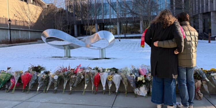 Senior Zoe Kass and her boyfriend leave flowers Dec. 16 at the engineering building at Brown University in Providence, Rhode Island. They fled the building Dec. 13 when a shooter opened fire during a finals study session.