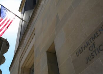 The US Department of Justice building and the American flag stand in the sun in Washington, DC.