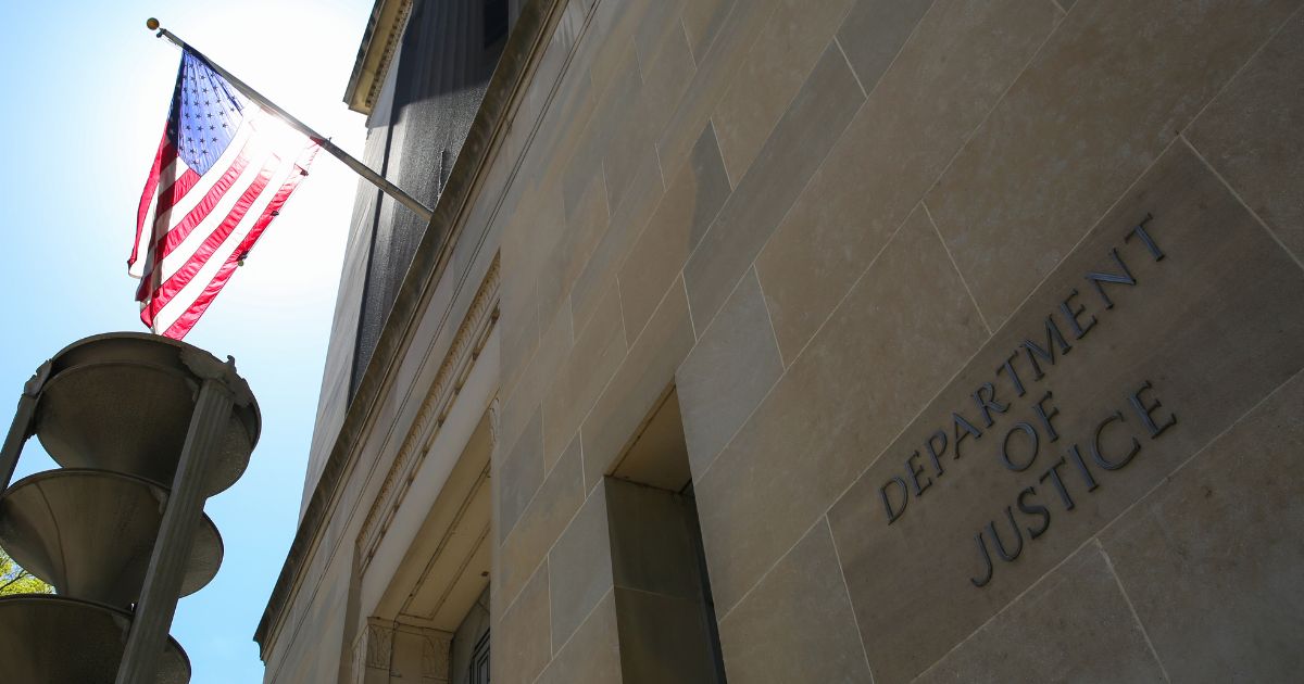 The US Department of Justice building and the American flag stand in the sun in Washington, DC.