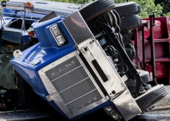 A rolled over semi-truck sits in the road.