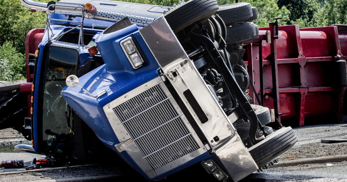 A rolled over semi-truck sits in the road.