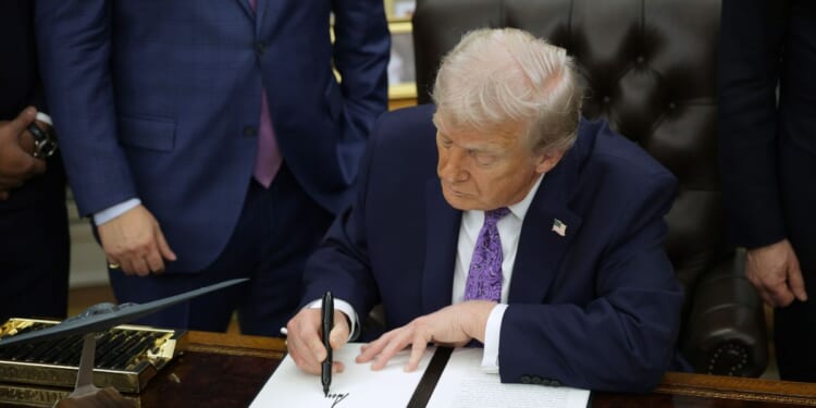 President Donald Trump signs an executive order in the Oval Office of the White House on Dec. 11, 2025, in Washington, D.C.