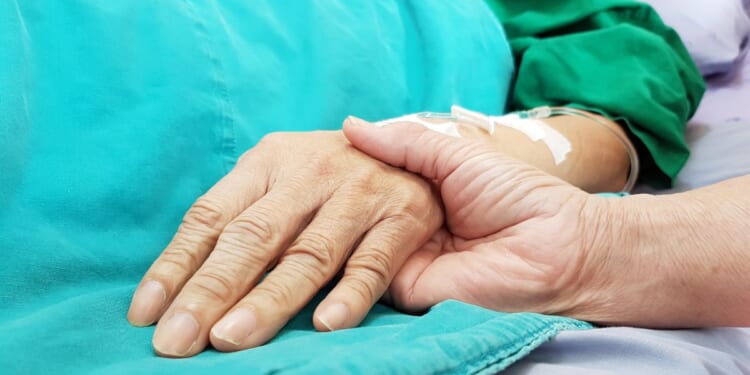 An oncologist doctor holds a patient's hand at a hospital.