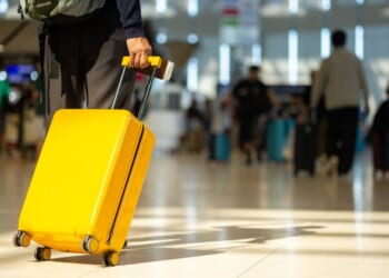 A traveler pulls his suitcase behind him at an airport.