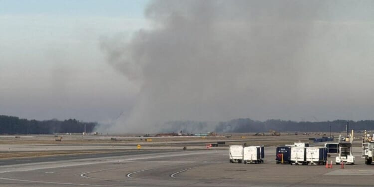 Smoke billows near a Dulles International Airport runway in Virginia on Dec. 13, 2025.