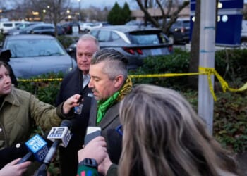 Multnomah County District Attorney Nathan Vasquez, center, speaks to the media Thursday following reports that federal immigration officers shot and wounded two vehicle occupants in Portland, Oregon.