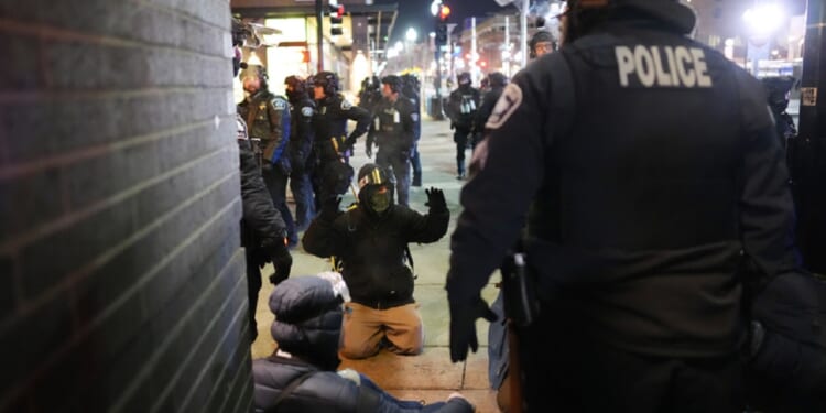 A protester on the ground raises his arms as law enforcement officers make arrests after Wednesday declaring an unlawful assembly during an anti-ICE demonstration in Minneapolis outside the Graduate by Hilton Minneapolis.