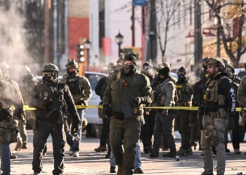 Federal agents stand near police tape as demonstrators gather near the site of where state and local authorities say a man was shot by federal agents earlier in the morning in Minneapolis, Minnesota, on Jan. 24, 2026.