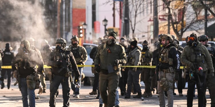Federal agents stand near police tape as demonstrators gather near the site of where state and local authorities say a man was shot by federal agents earlier in the morning in Minneapolis, Minnesota, on Jan. 24, 2026.