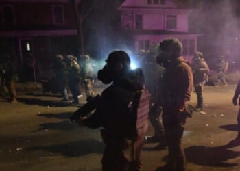 Federal law enforcement agents and police officers in riot gear walk amid smoke from crowd control devices after protests broke out following the shooting of a Venezuelan man by a Immigration and Customs Enforcement agent in Minneapolis, Minnesota, on Jan. 14, 2026.