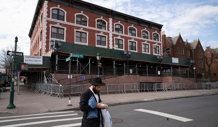 A man passes the Chabad-Lubavitch World Headquarters in the Crown Heights neighborhood of Brooklyn, April 7, 2020 in New York. (AP Photo/Mark Lennihan, File)