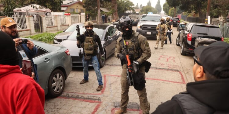 Border Patrol agents and other law enforcement clear the way for an authorized car to pass while investigating a shooting involving a federal agent on Wednesday morning in Willowbrook, California, on Jan. 21, 2026.
