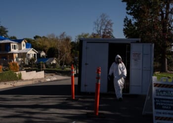 A worker in protective gear exits a storage container at a cleanup site on Dec. 3, 2025, months after the Eaton Fire, in Altadena, California.