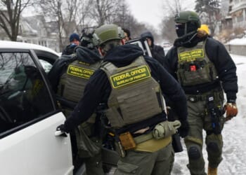 Federal agents return to their car after a patrol in the Frogtown neighborhood while anti-ICE activists warn the community about their presence and oppose ongoing Immigration and Customs Enforcement detentions, part of heightened tensions following a federal immigration enforcement surge and recent shooting involving an ICE officer in St. Paul, Minnesota, on Jan. 16, 2026.