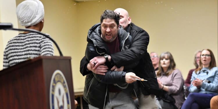 A man later identified as Anthony J. Kazmierczak, 55, is tackled after spraying a substance now believed to be apple cider vinegar at Democratic Rep. Ilhan Omar during a town hall she was hosting Tuesday in Minneapolis, Minnesota.