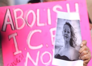 A protester holds an "Abolish ICE" sign and a picture of Renee Good, who was fatally shot Wednesday while apparently driving her car toward a federal immigration officer. Good has been portrayed as an innocent observer, but new information indicates she was active in a nationwide activist group called "ICE Watch."