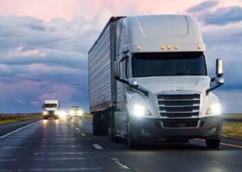 A stock photo of a tractor-trailer rolling down a highway.