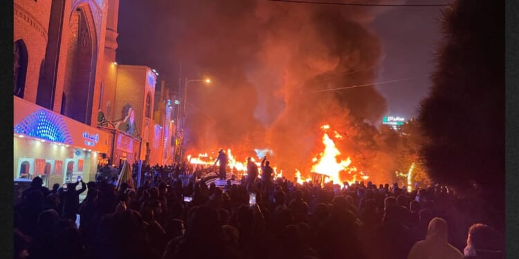 Iranian protesters gather around burning cars near a mosque while blocking a street during a protest in Tehran, Iran, on Jan. 8. The nationwide demonstrations spread across cities with slogans turning from economic grievances to political and anti-government calls. The protests were met by a violent crackdown in which thousands were reportedly killed, according to human rights groups.